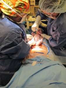 Médicos practicando una cesárea natural con presencia del padre en el quirófano