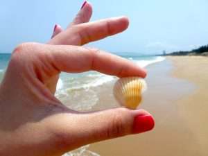 manos mostrando uñas pintadas en la playa