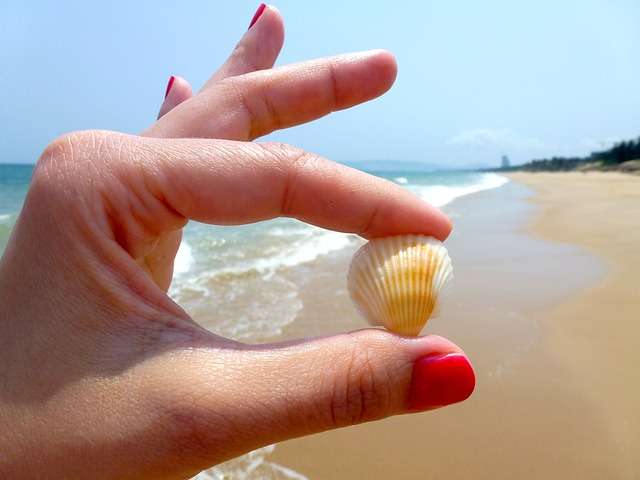 manos mostrando uñas pintadas en la playa