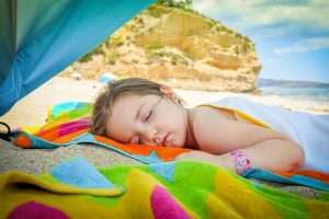 niño duerme siesta en la playa verano