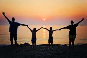 imagen de una familia dados de la mano en una puesta de sol