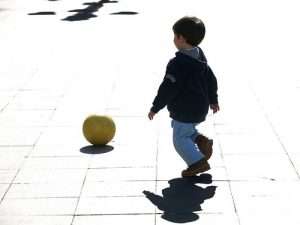 niño que juega a la pelota en la calle