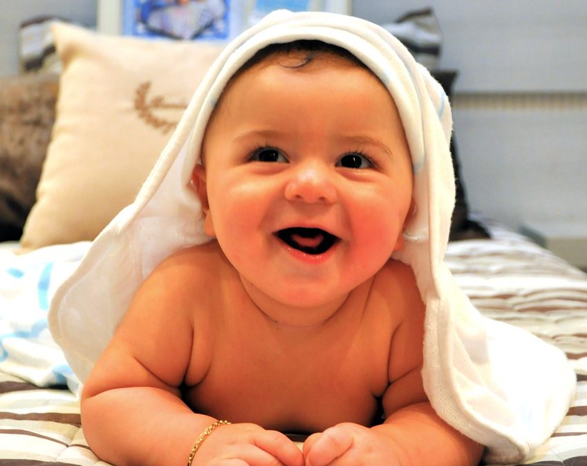bebé feliz tumbado boca arriba después del baño para el cuidado de la piel e higiene del bebe