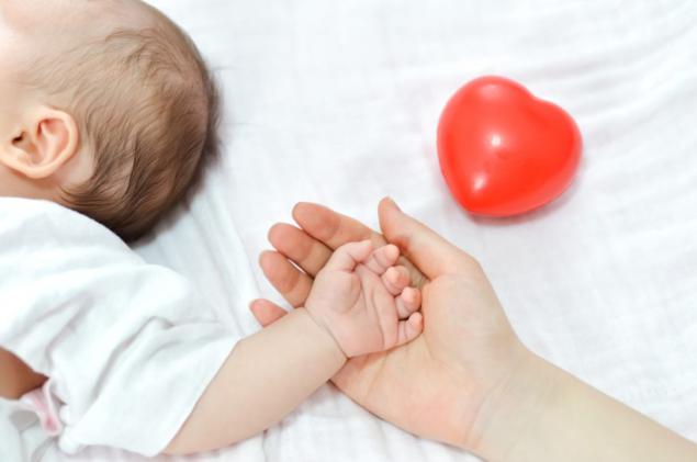 madre da mano a bebé con un corazon pintado detras