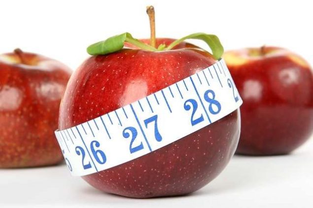 manzana con cinta métrica com mención a dietas, comida y engordar o adelgazar