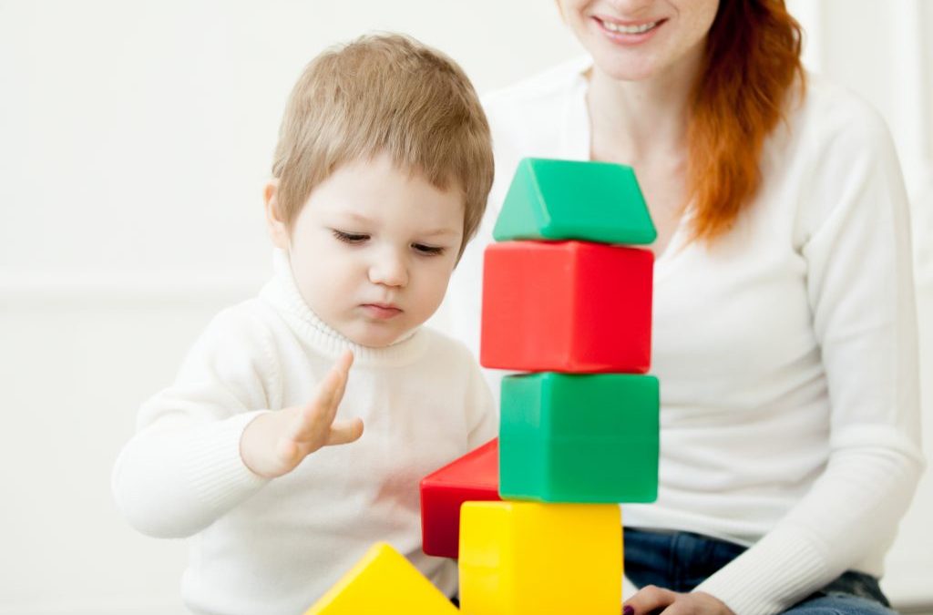 bebé niño jugando con cubos con una chica joven para hablar de consejos elegir cuidadora