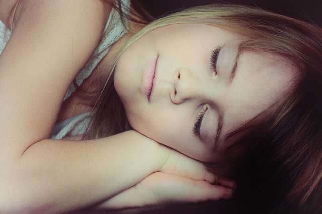 niña tumbada y dormida con sueño infantil o fiebre