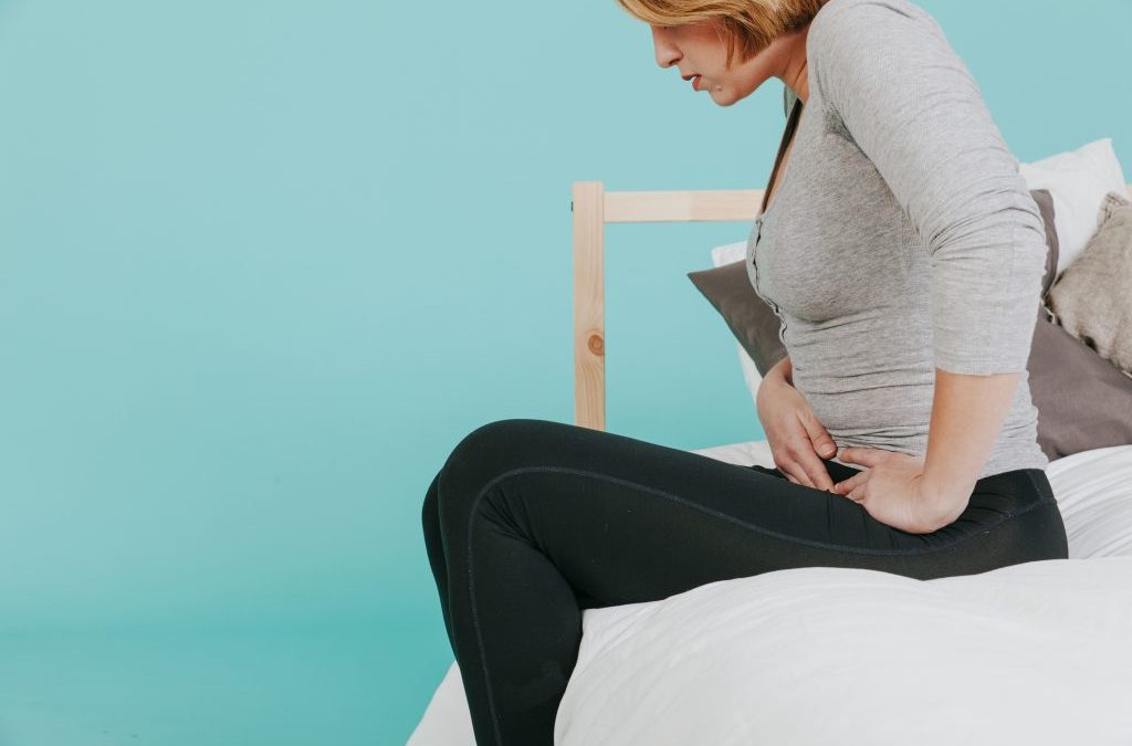 imagen de una mujer tocándose el abdomen con mueca de dolor para hablar de pruebas para detectar la endometriosis dolor de tripa