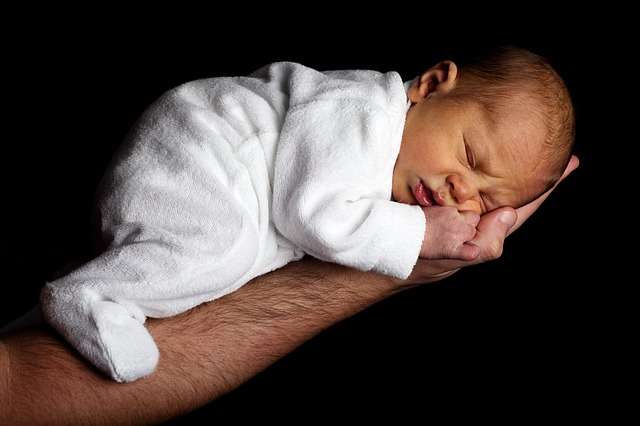 bebé boca abajo apoyando tripa en brazo de su padre recién nacido gases