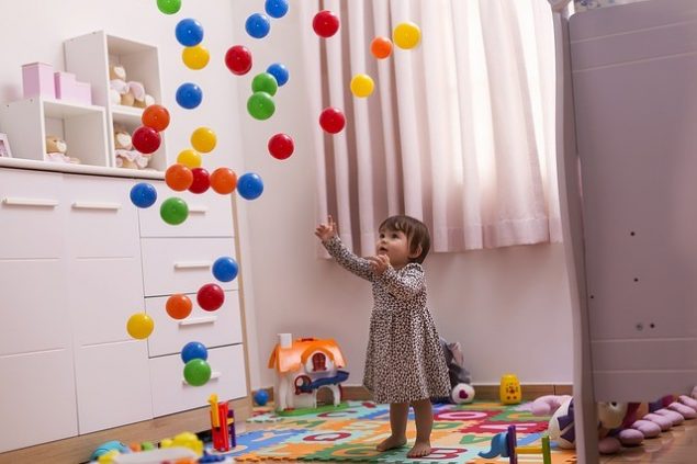 niña jugando en un cuarto infantil con bolas y otros juguetes