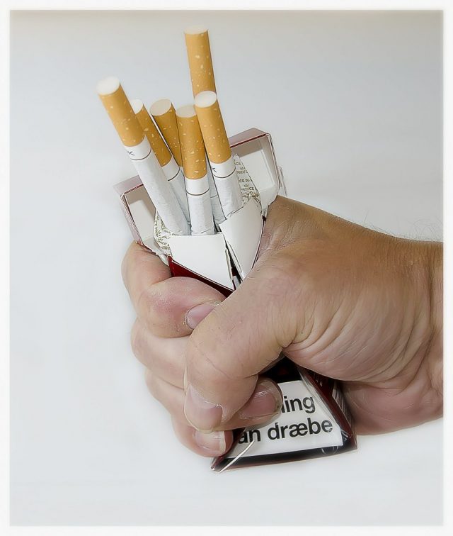 mano apretando carton de tabaco para dejar de fumar