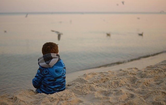 niño pensativo en mar playa