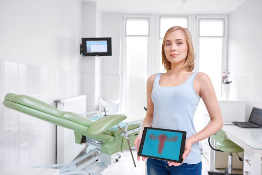 mujer muestra dibujo de utero y ovarios en tableta en consulta del médico