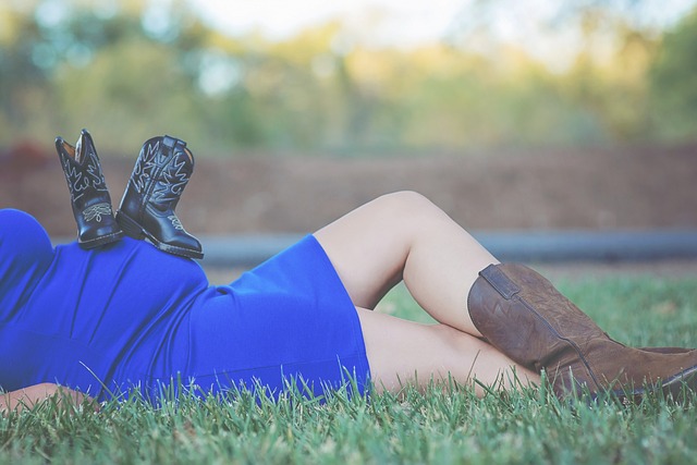 embarazada tumbada en campo con botas y calzado sobre la tripa